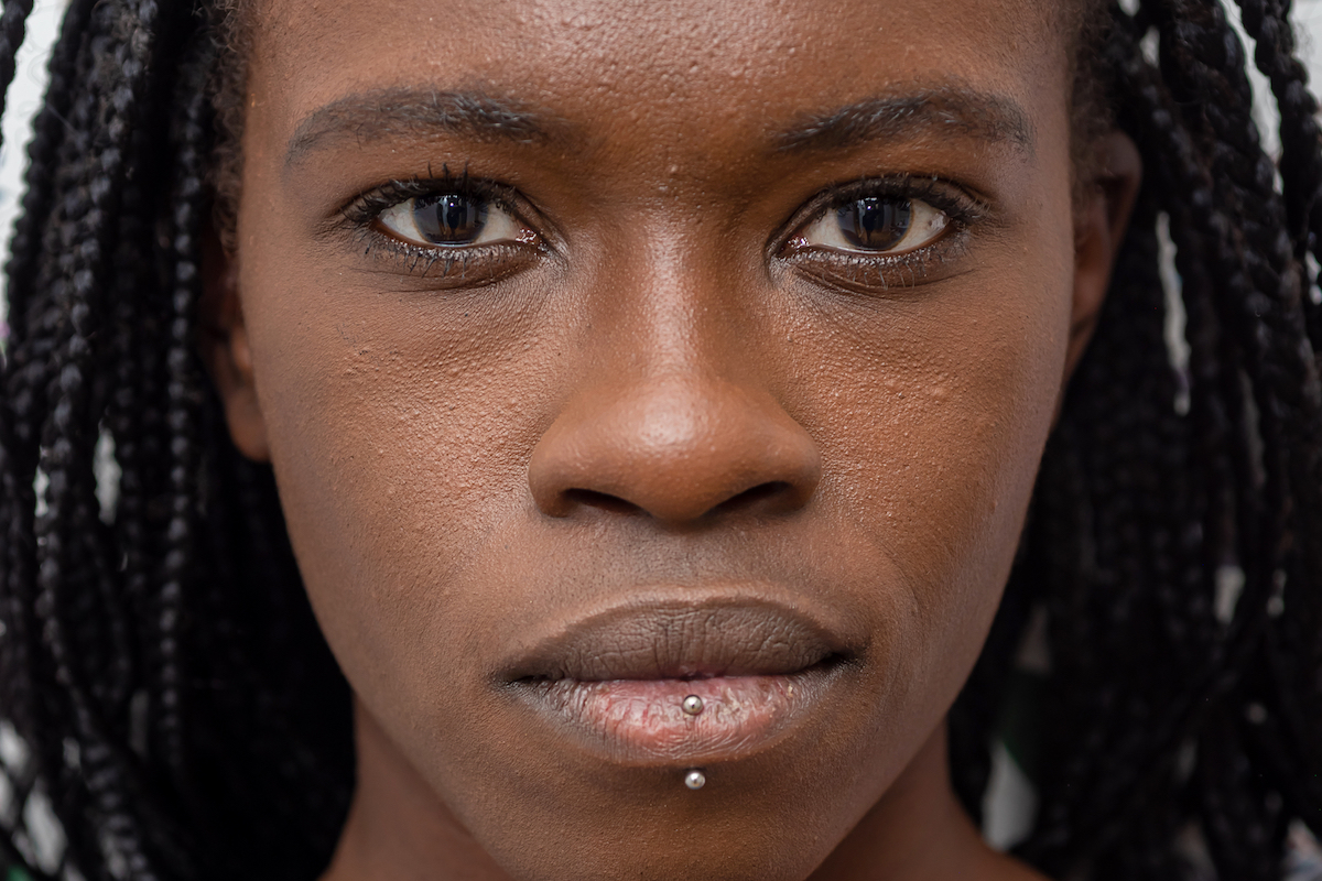 Headshot of determined African American female with black braids and piercing looking at camera